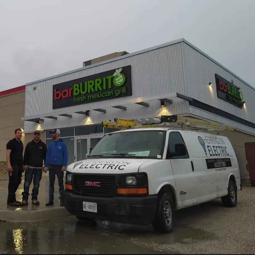Ryan and the Herrington Electric crew beside their service van outside a restaurant project