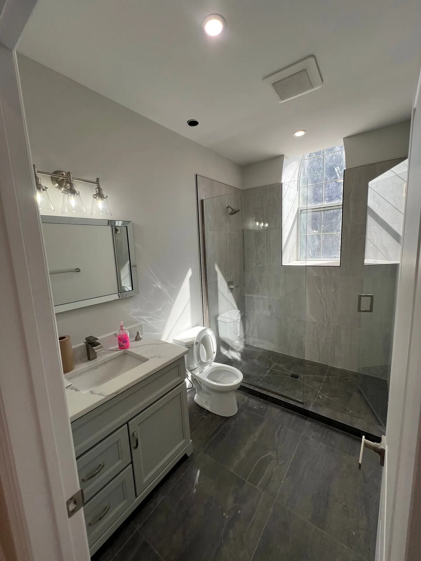 Finished bathroom with vanity lighting, a ceiling pot light, and an exhaust fan.