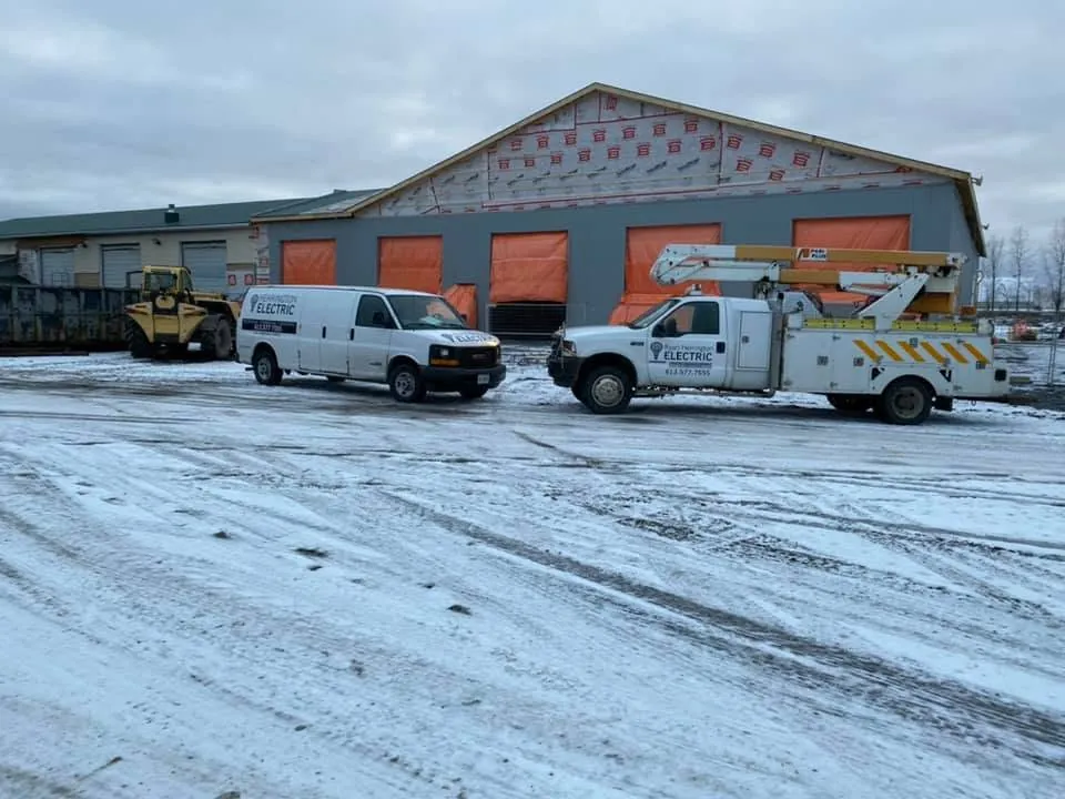 Herrington Electric van and bucket truck outside a commercial construction project in winter