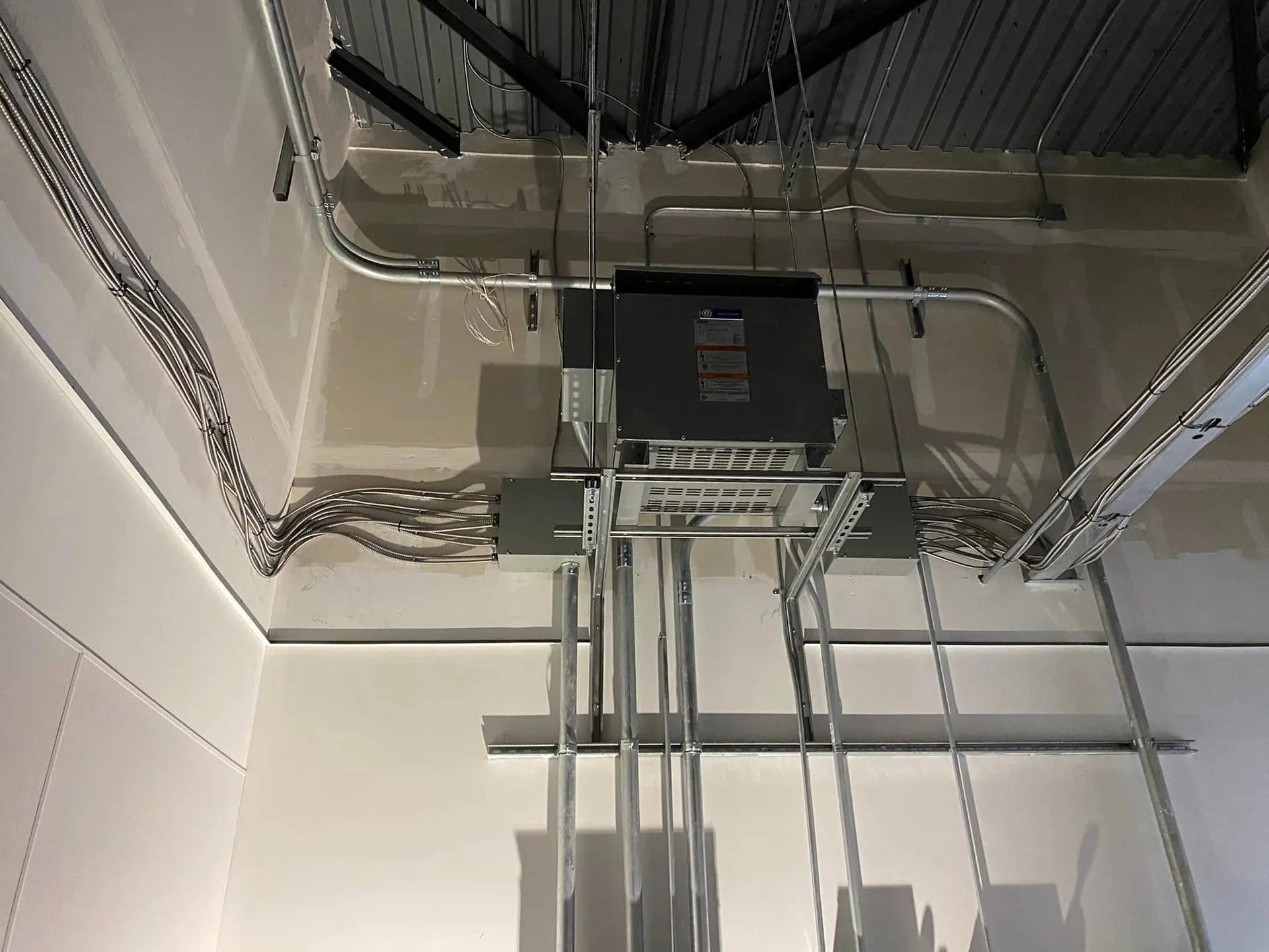 Commercial service equipment with organized conduit runs in an electrical room.