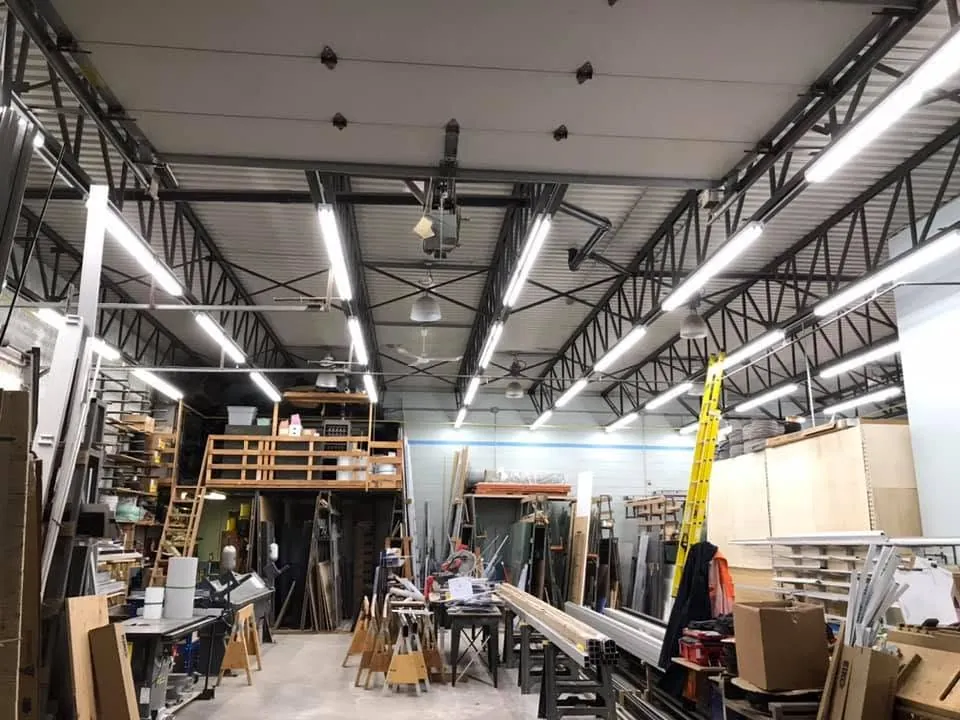 Commercial workshop interior illuminated by rows of suspended LED fixtures.