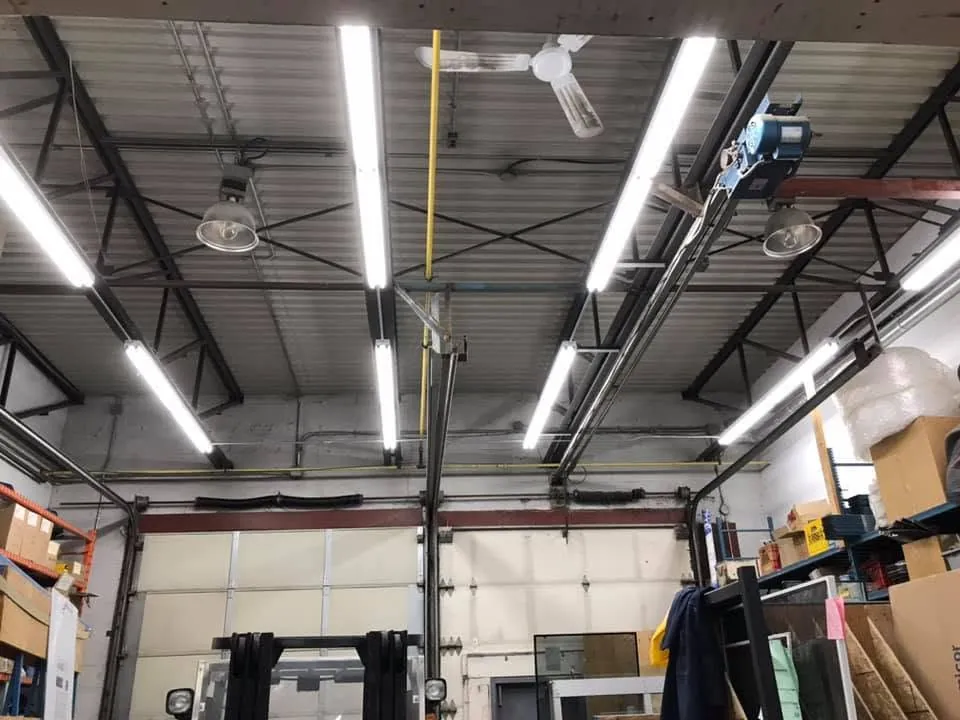 Rows of bright LED fixtures lighting a commercial workshop with exposed steel roof framing.