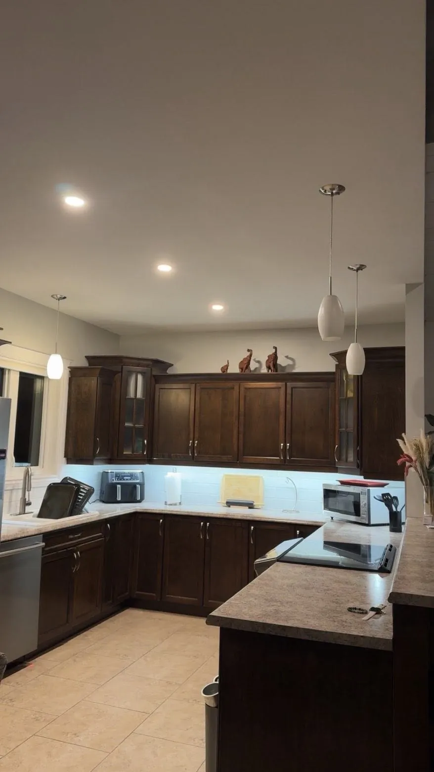 Finished kitchen with pot lights, pendant fixtures, and illuminated work surfaces.