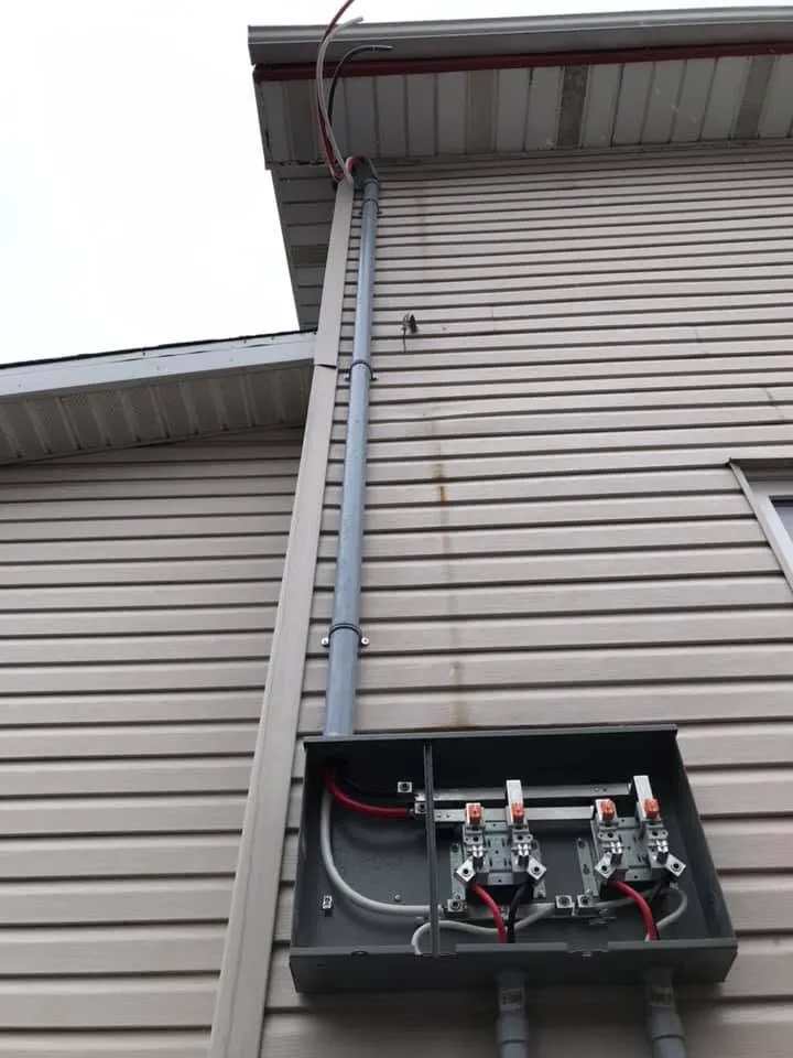 Residential meter base and overhead service mast mounted on exterior siding.