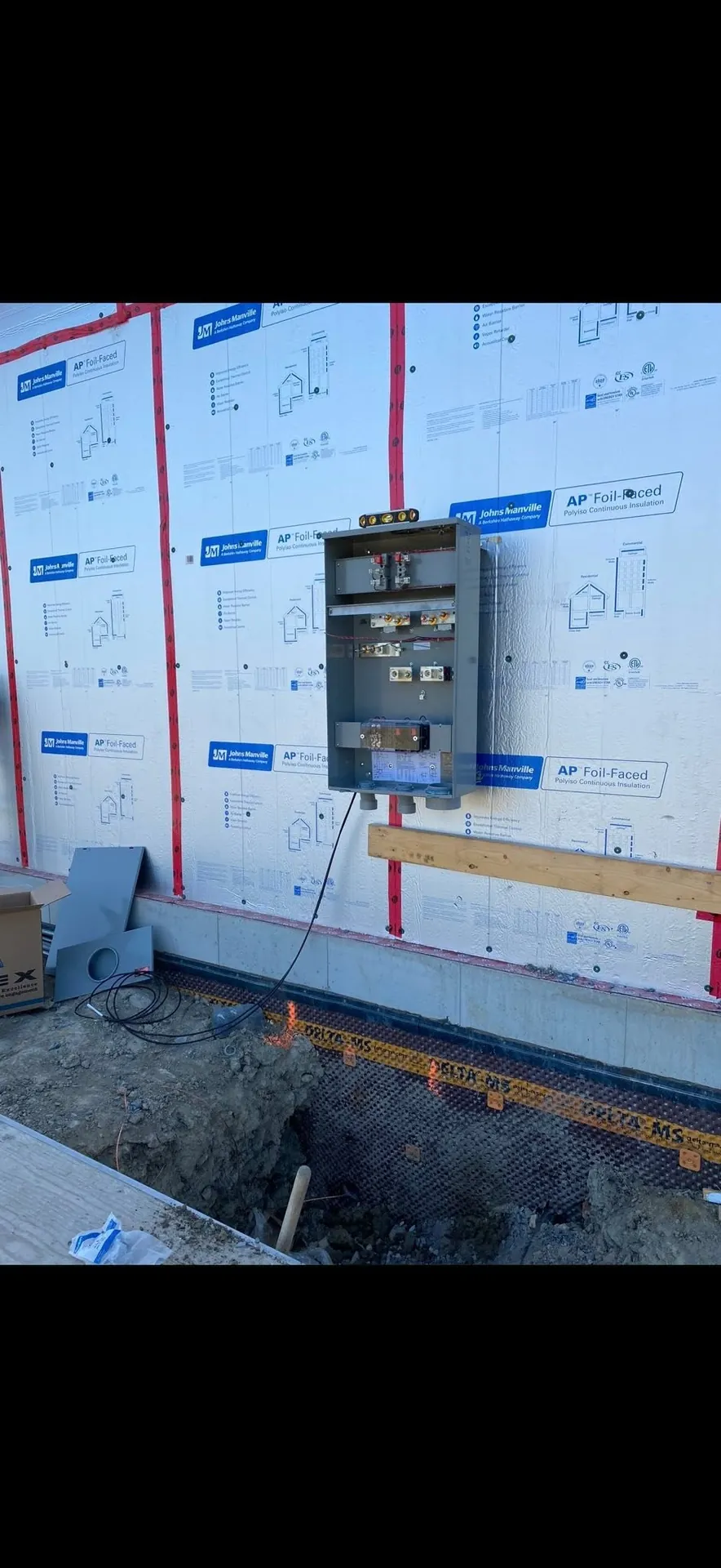 Meter base and electrical service conduit installed on a new building exterior.