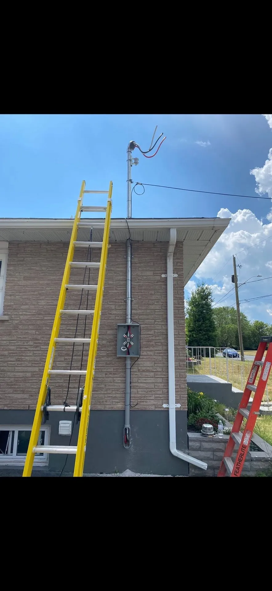 Overhead electrical service mast being installed on a commercial building.