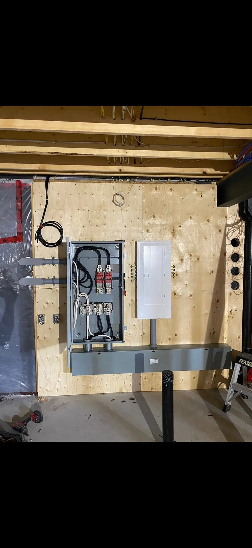 Electrical panel and adjacent service equipment mounted on a utility-room backboard.