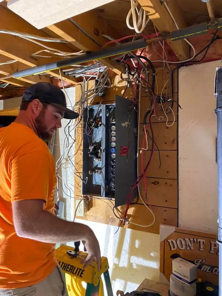 Electrician working on a residential breaker panel installation.
