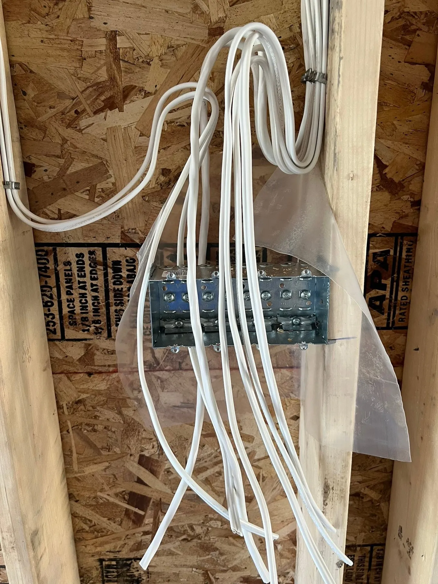 Residential breaker panel and coiled branch wiring during rough-in.