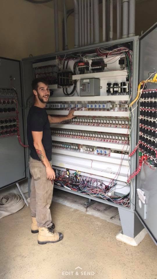 Ryan Herrington beside an open electrical control panel