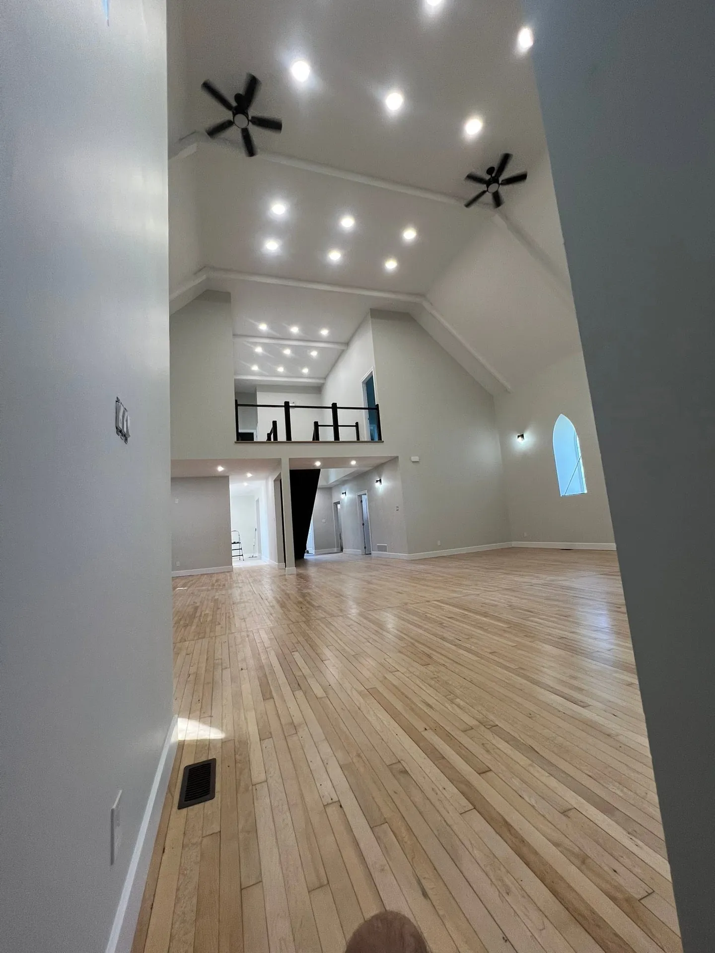 Vaulted great room illuminated by pot lights, ceiling fans, and hanging fixtures.